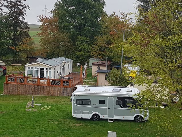 Wohnmobil auf dem Stellplatz zwischen Bäumen